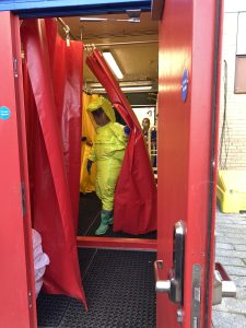 A person in a yellow hazard suit going through a red curtain