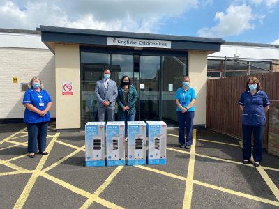 Three nurses and a man and a woman in front of four air conditioning boxes