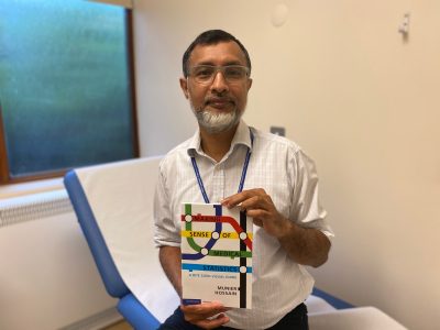 A man sitting on a medical couch holding a medical textbook