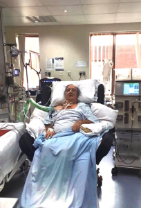 A patient awake in a bed surrounded by monitors, wires and machines.