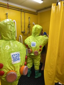 People in a yellow hazard suit being washed down