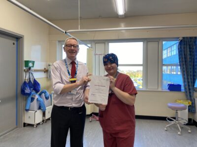 Two people standing in a hospital holding a certificate.