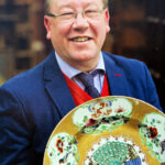 A man holding a large decorative plate