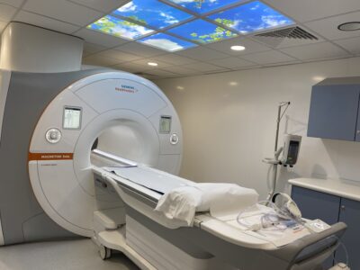 A large white MRI scanner, with light panels above showing an image of the sky