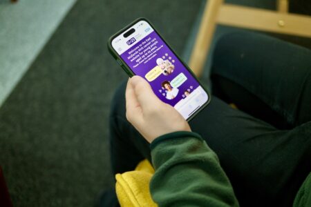 young person holding a mobile phone with the cancer website displayed