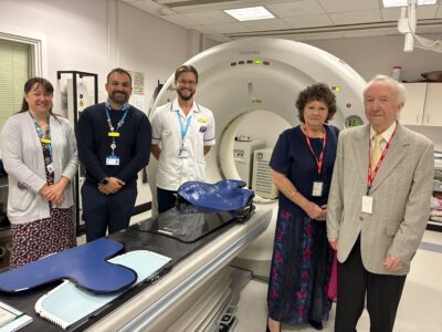 Five people stood by a hospital bed and the head and neck cradle 