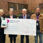 four people stood with a giant cheque