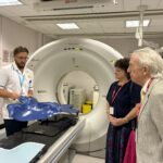 three people looking at a head and neck cradle on a hospital bed