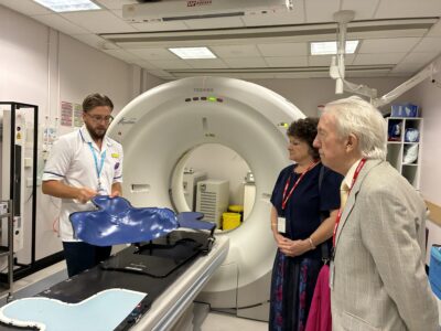 three people looking at a head and neck cradle on a hospital bed