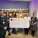 six people stood with a big cheque in a hospital