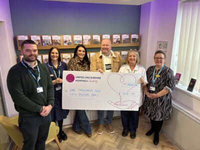 six people stood with a big cheque in a hospital
