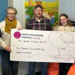 Four people stood behind a giant cheque