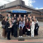 The group of visiting students outsude the main entrance of Lincoln County Hospital. The hospital's blue sign is in the background.